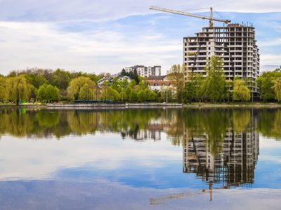 New modern skyscraper under construction on the bank of a lake. Concrete building reflection in water